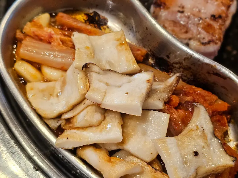 불판 한켠에 놓인 김치, 마늘, 버섯