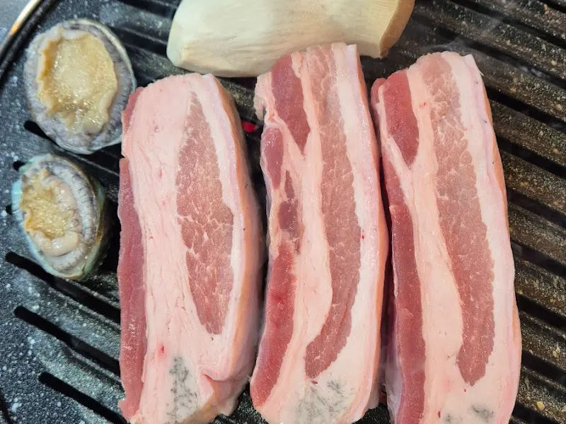 숯불 위에서 익어가는 흑돼지 오겹살과 싱싱한 전복