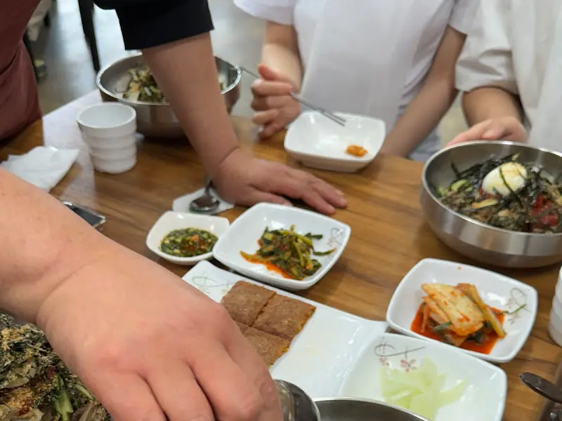 테이블 가득 차려진 밑반찬과 메밀 막국수