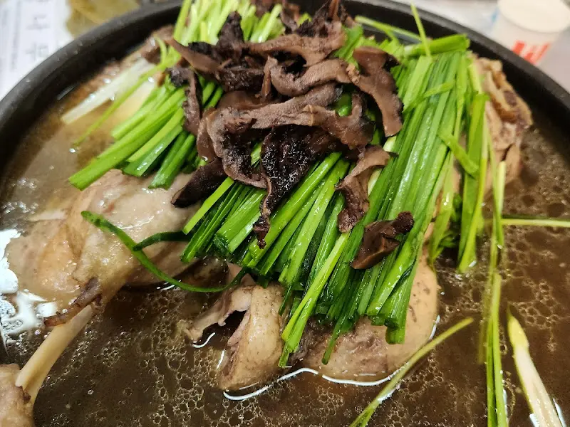 능이버섯과 부추가 듬뿍 올라간 유황오리 백숙 클로즈업