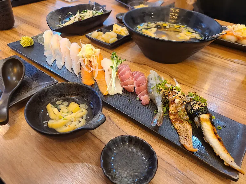 연어, 샐러드, 초밥, 우동이 함께 차려진 한 상