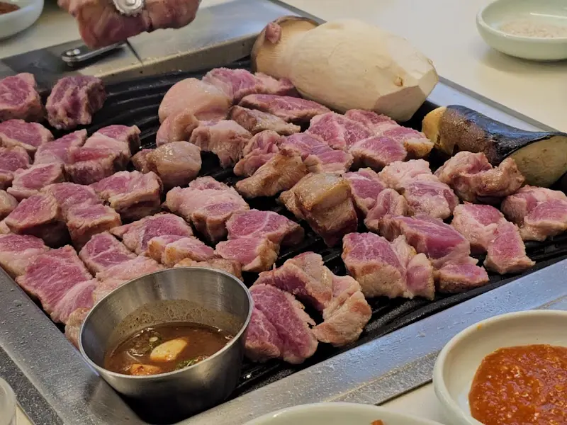 숯불 위에서 구워지는 두툼한 목살과 채소