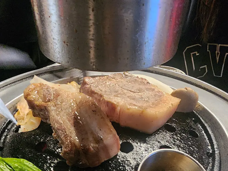 두툼한 흑돼지 삼겹살이 불판 위에서 구워지는 모습