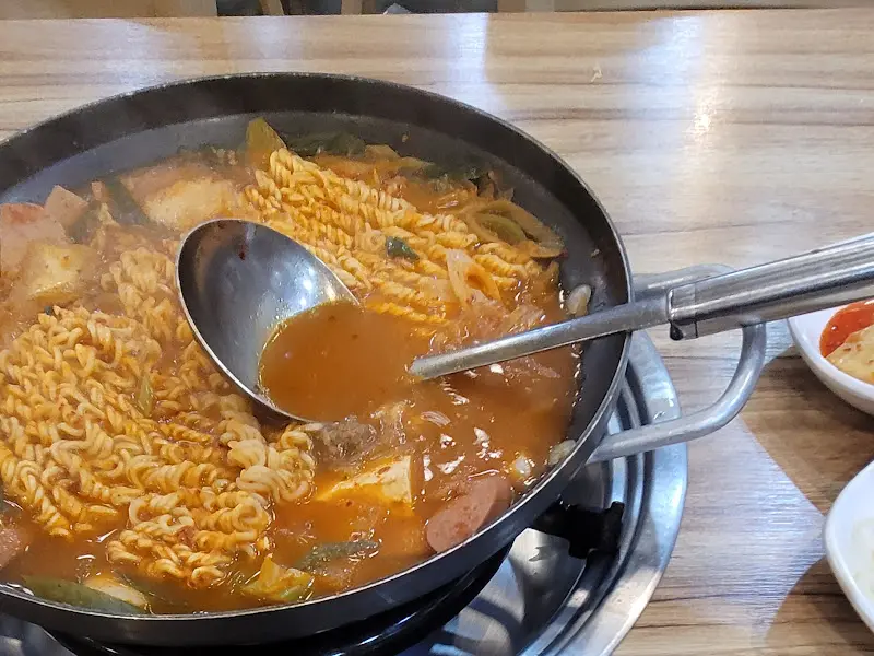 국자로 부대찌개 국물을 뜨는 모습