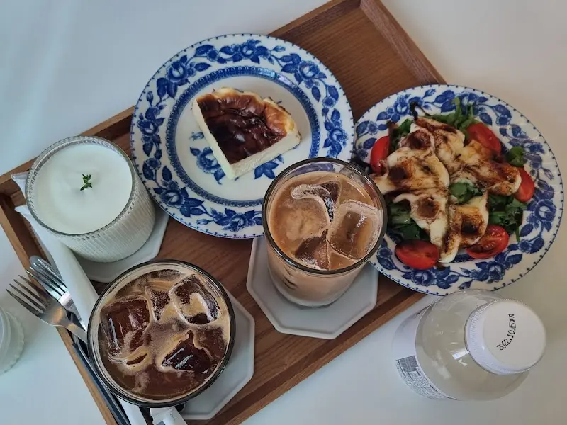 산양유 요거트, 치즈 와플, 아메리카노, 치즈 케이크가 한 상 가득 차려진 모습