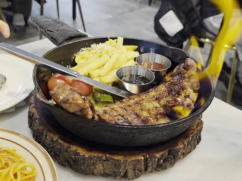 뜨거운 팬에 담겨져 나온 돼지고기 스테이크