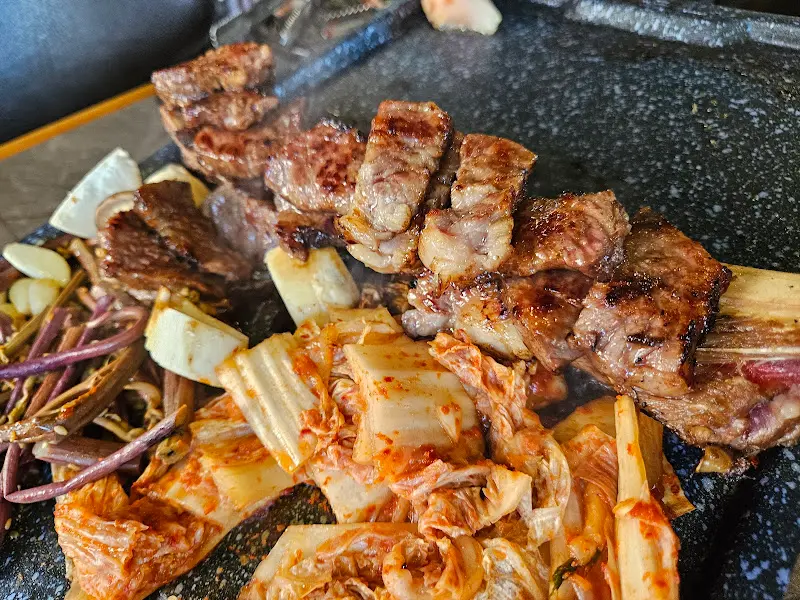 불판 위에서 지글거리는 우대갈비, 김치, 고사리의 조화로운 모습이 식욕을 자극한다.
