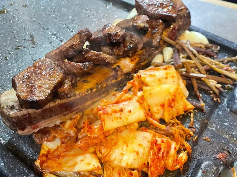 잘 구워진 우대갈비와 김치가 조화롭게 놓여진 모습, 윤기가 흐르는 고기가 먹음직스럽다.