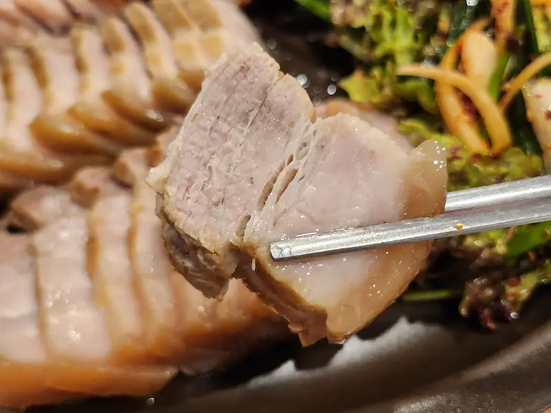 젓가락으로 집어 올린 보쌈 한 점