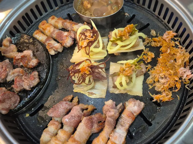 불판 위 구워지는 삼겹살과 곁들임