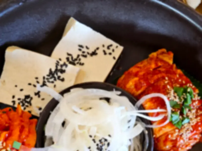 마늘 보쌈과 함께 제공되는 곁들임 반찬들. 신선한 채소와 김치가 정갈하게 담겨 있다.