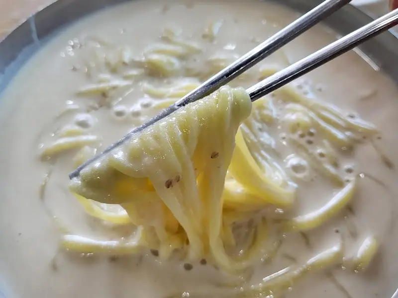 젓가락으로 콩국수를 들어 올리는 모습