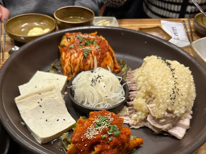 다양한 곁들임 메뉴와 함께 세팅된 마늘 보쌈 한 접시 클로즈업 샷