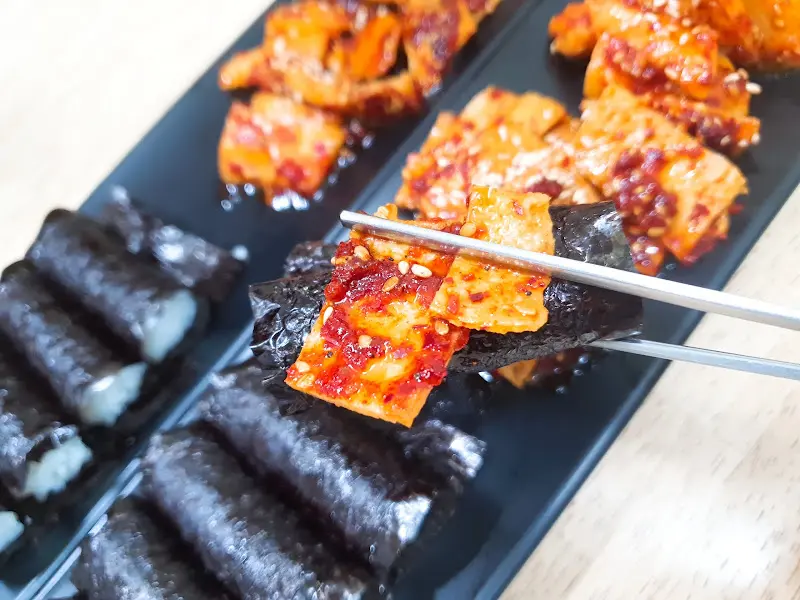 충무김밥에 오징어 무침을 올려 한 입