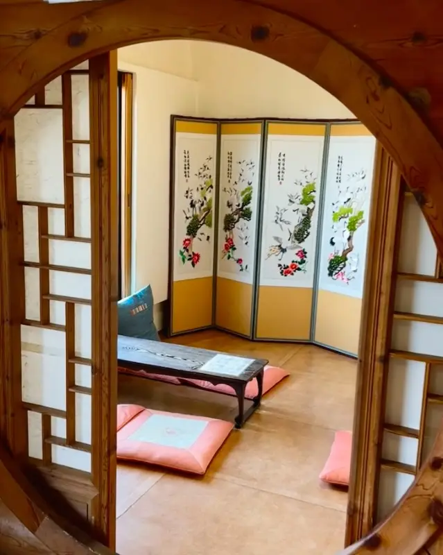 둥근 창문을 통해 보이는 꽃자리 내부의 아늑한 좌식 공간