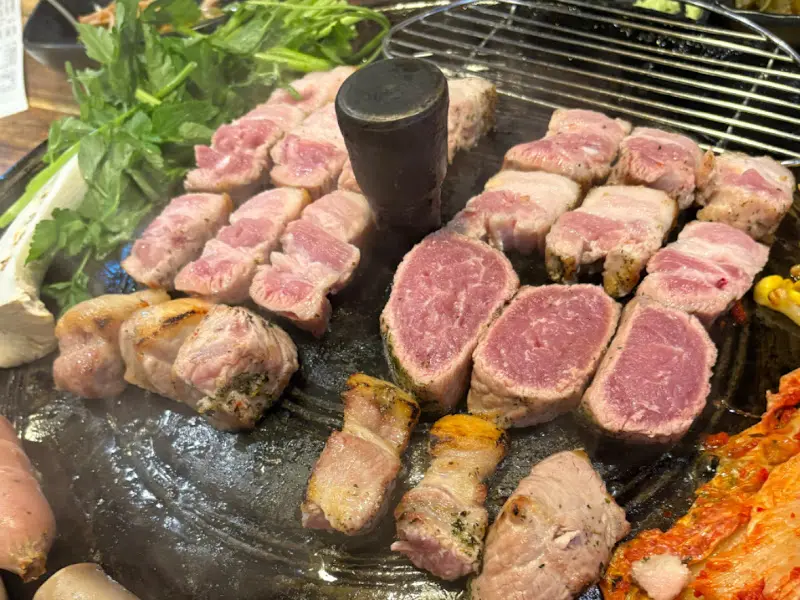 솥뚜껑에 구워지는 삼겹살, 김치, 콩나물