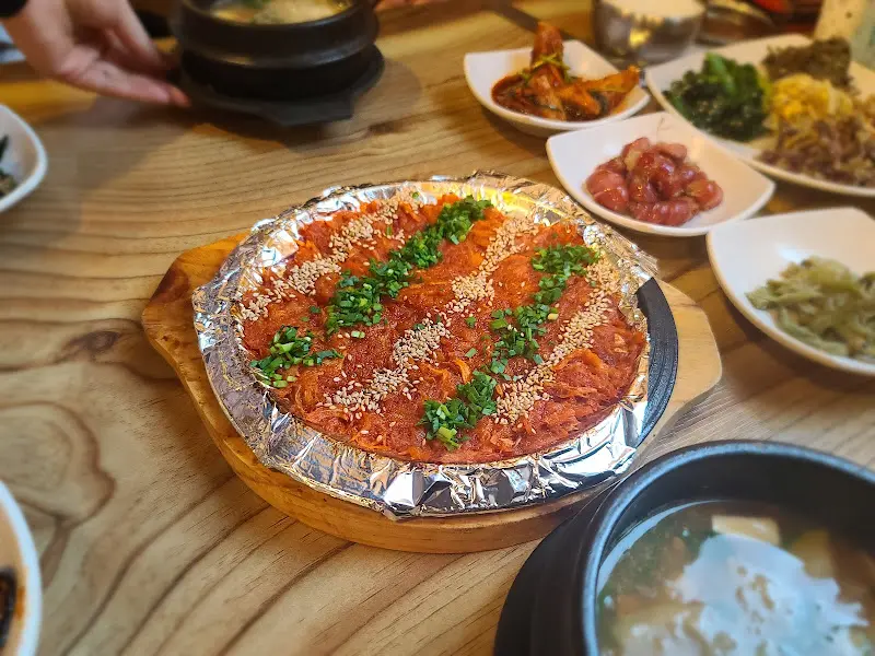 붉은 양념과 깨가 뿌려진 더덕구이