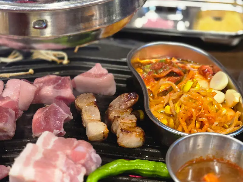 불판 위에서 익어가는 삼겹살, 김치, 콩나물