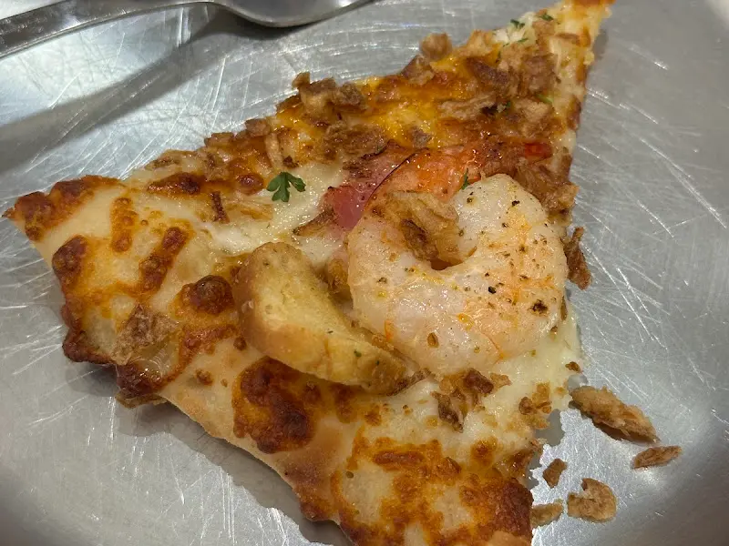 탱글탱글한 새우가 듬뿍 올라간 갈릭 슈림프 피자 한 조각