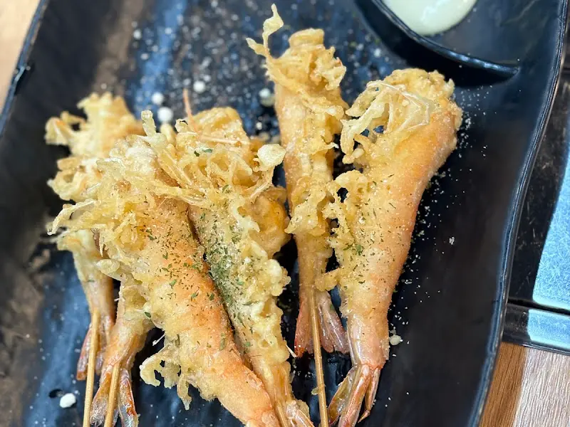 검정 접시에 가지런히 담긴 새우 튀김의 모습