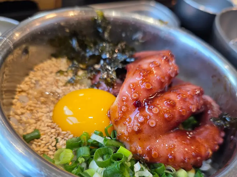 윤기가 흐르는 큼지막한 문어가 솥밥 위에 얹혀진 모습