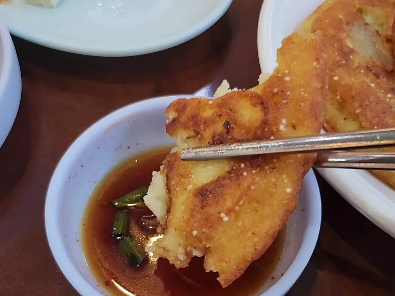 녹두전을 간장 양념에 찍어 먹는 모습