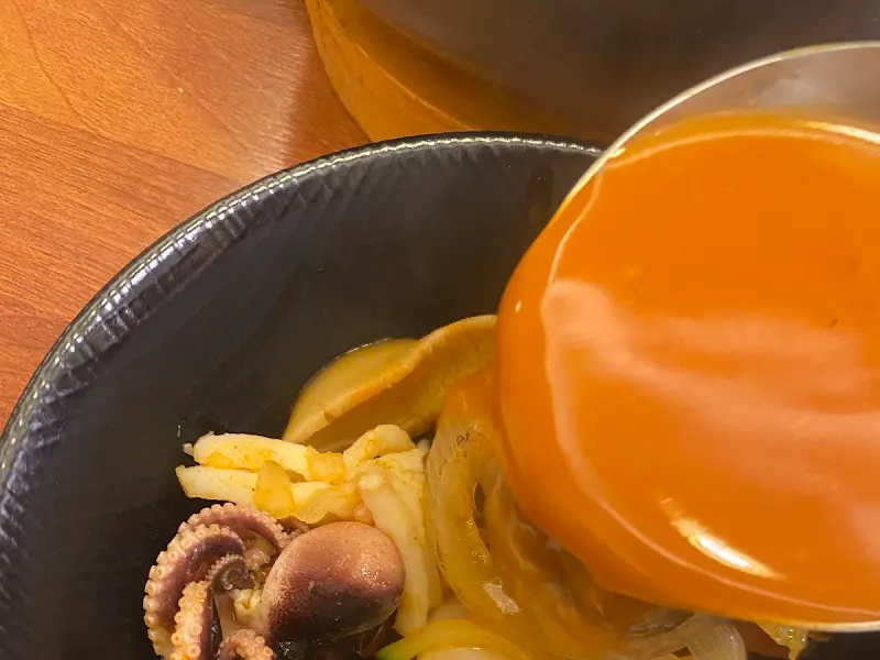 국자를 사용하여 짬뽕 국물을 뜨는 모습