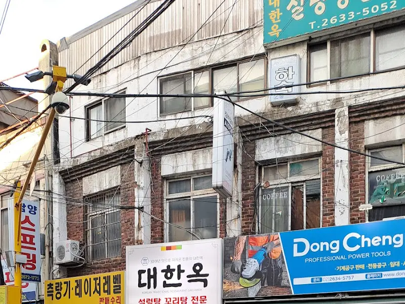 허름한 건물 외관과 푸른색 간판이 눈에 띄는 대한옥 외부 전경