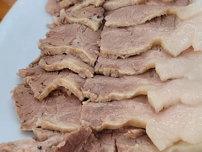 얇게 썰린 수육이 가지런히 놓여 있다. 살코기와 비계의 비율이 적절해 보인다.