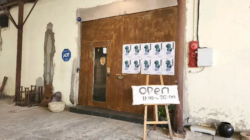 카페 외부 전경: 낡은 철문과 오픈 안내판이 독특한 분위기를 자아낸다.