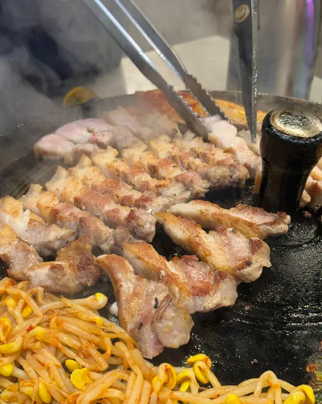 솥뚜껑에 구워지는 삼겹살과 김치