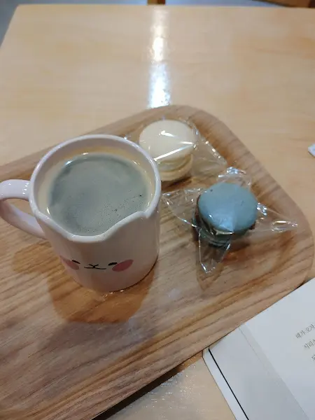 귀여운 컵에 담긴 커피와 마카롱