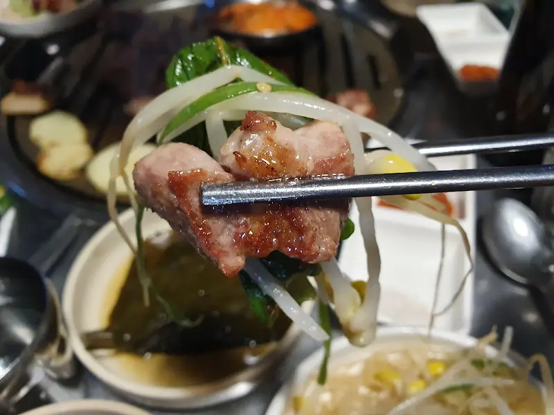 잘 익은 목살을 야채와 함께 쌈 싸먹는 모습