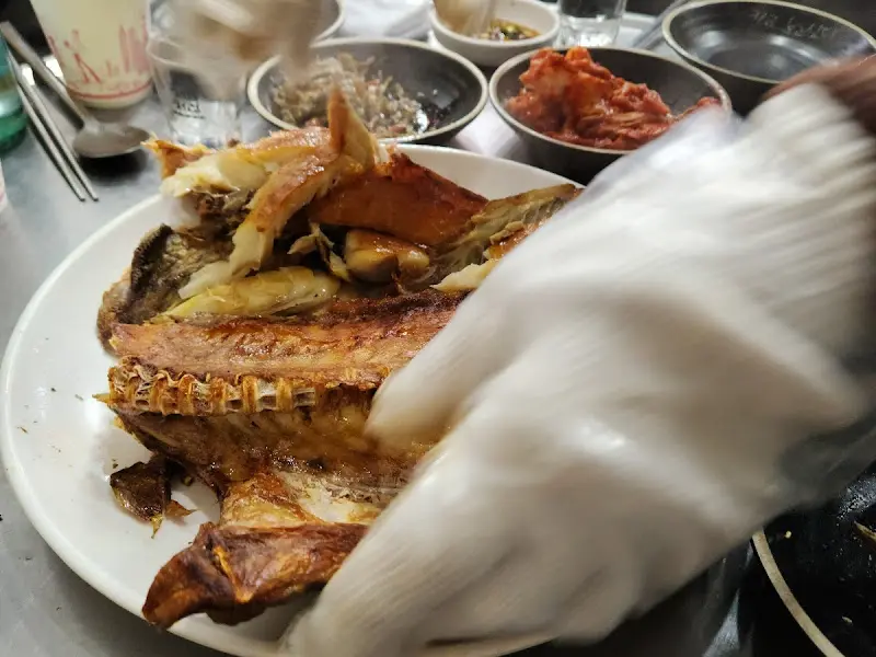 손으로 우럭구이를 먹기 좋게 찢는 모습