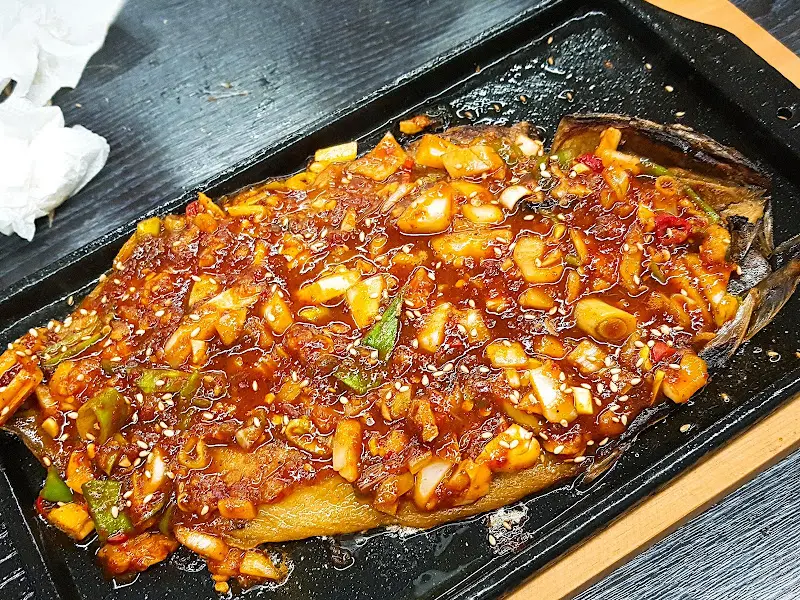 철판에 양념과 함께 구워진 생선