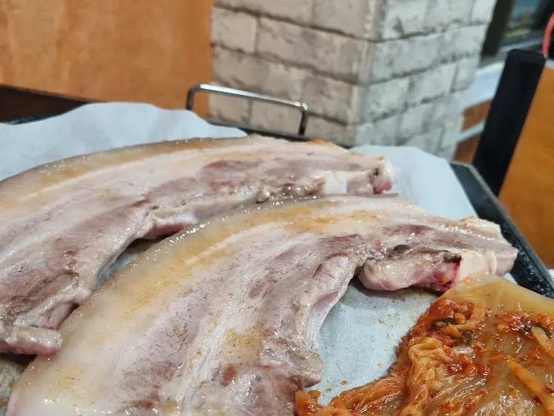 구워진 오겹살과 김치의 근접 사진