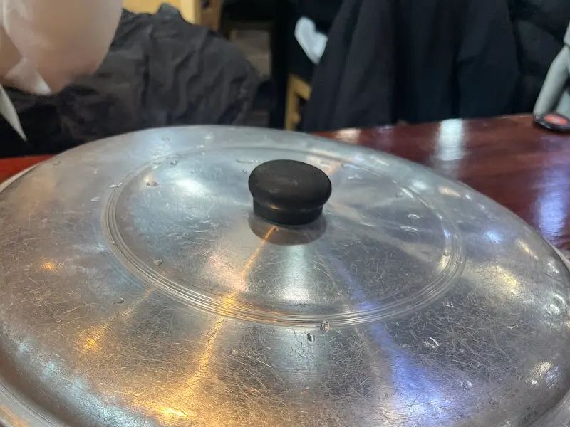 은색 냄비 뚜껑이 덮여진 부대찌개의 모습