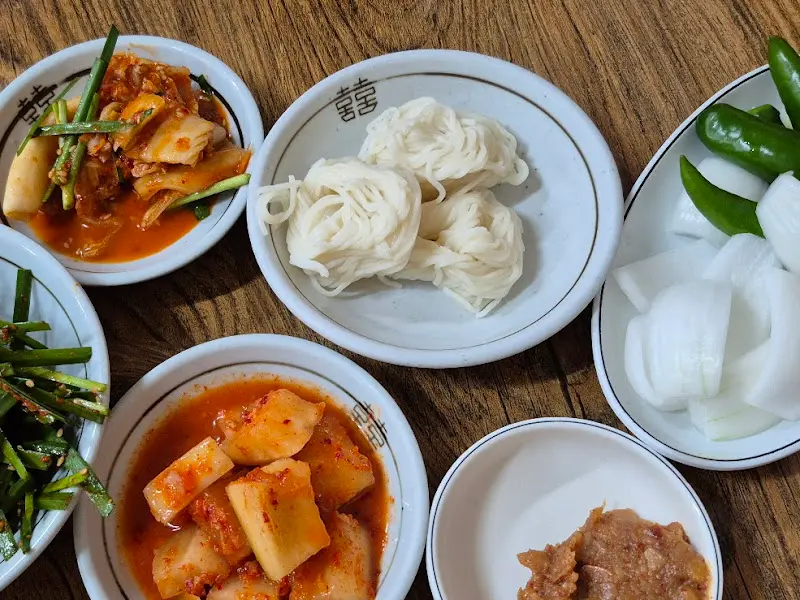 다채로운 밑반찬: 김치, 깍두기, 정구지 무침, 생양파, 풋고추