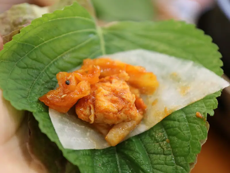 닭갈비를 깻잎에 싸서 먹는 모습