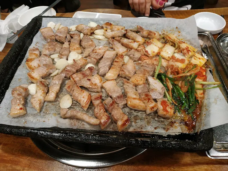 불판 가득 구워진 삼겹살과 김치, 부추