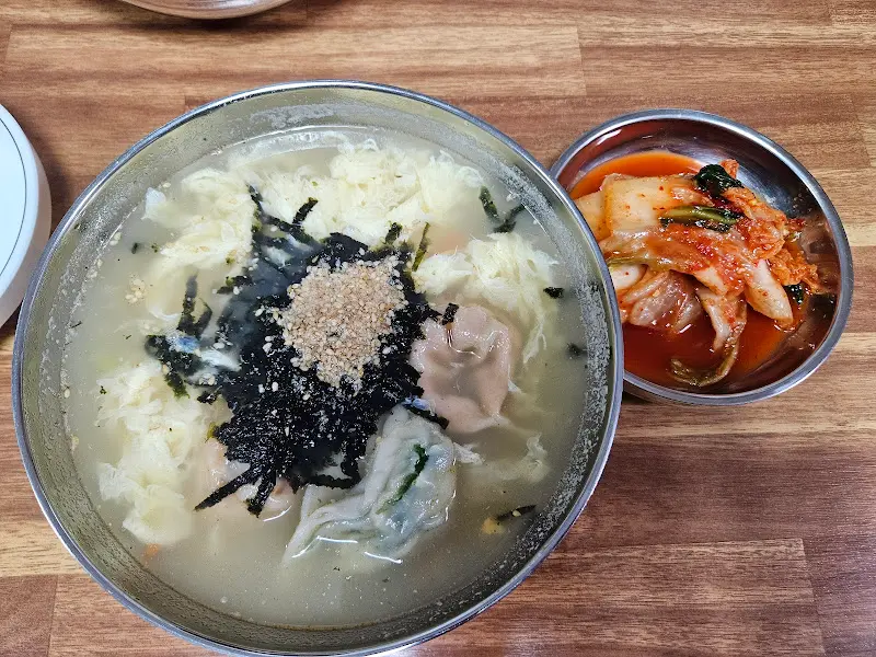 만두 칼국수와 김치가 함께 놓인 사진