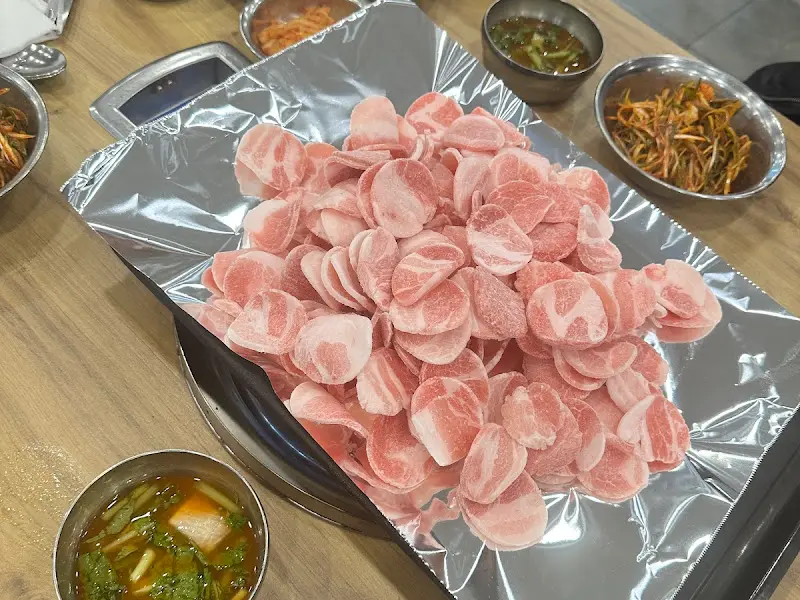 불판 위에 올려진 삼겹살과 주변 반찬들