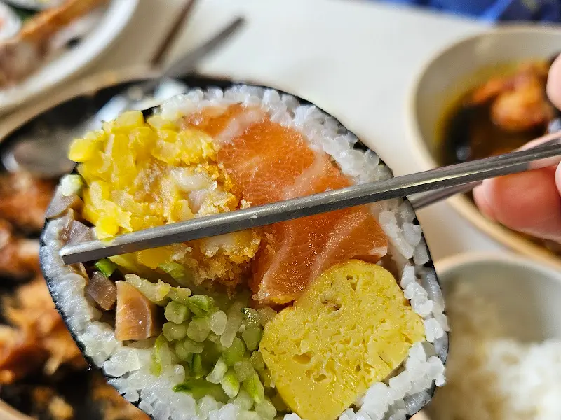 젓가락으로 집어 올린 연어 후토마끼의 단면