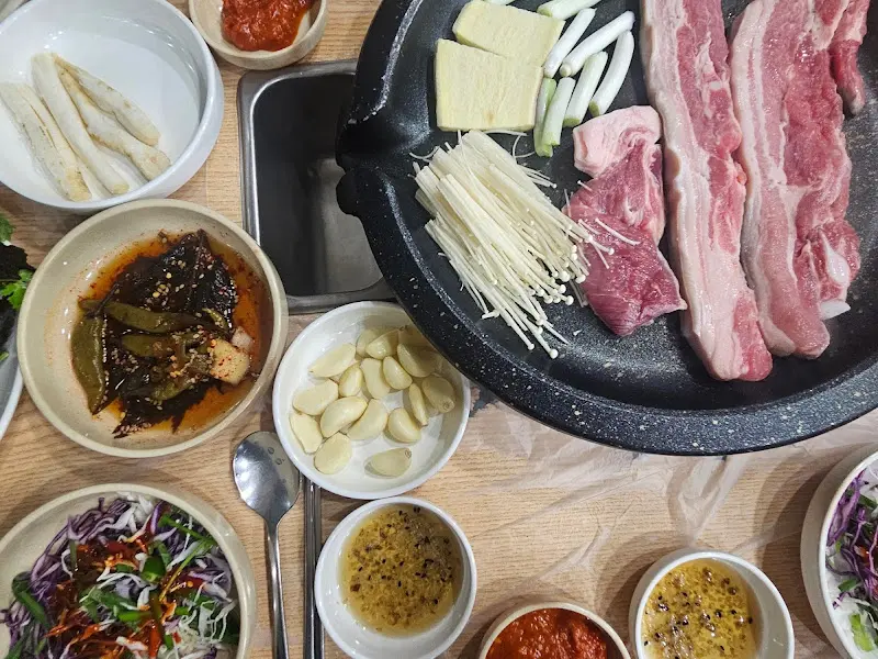 돌판 위에 구워지는 삼겹살과 다양한 채소