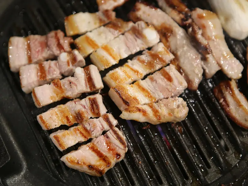 불판 위에서 노릇노릇하게 익어가는 삼겹살