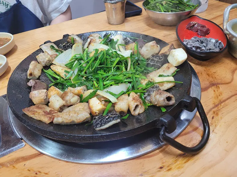 돌판 위에 곱창, 대창, 벌집양과 함께 부추, 양파 등이 구워지고 있는 모습