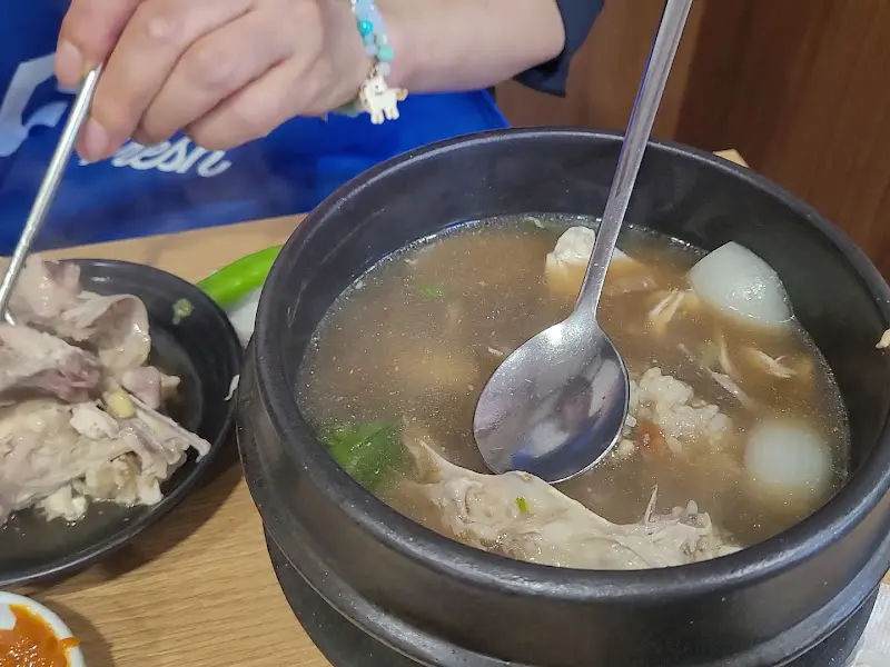 국물과 닭고기를 함께 떠먹는 모습