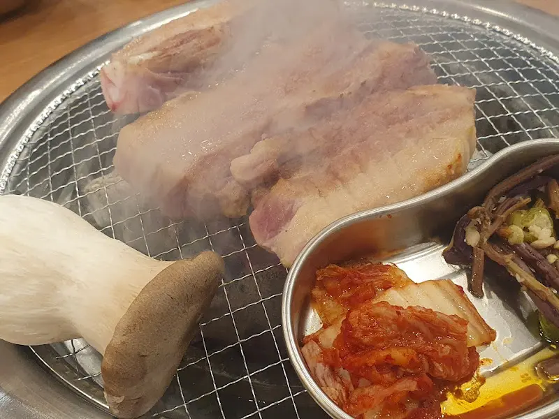불판 위에서 익어가는 삼겹살, 김치, 버섯
