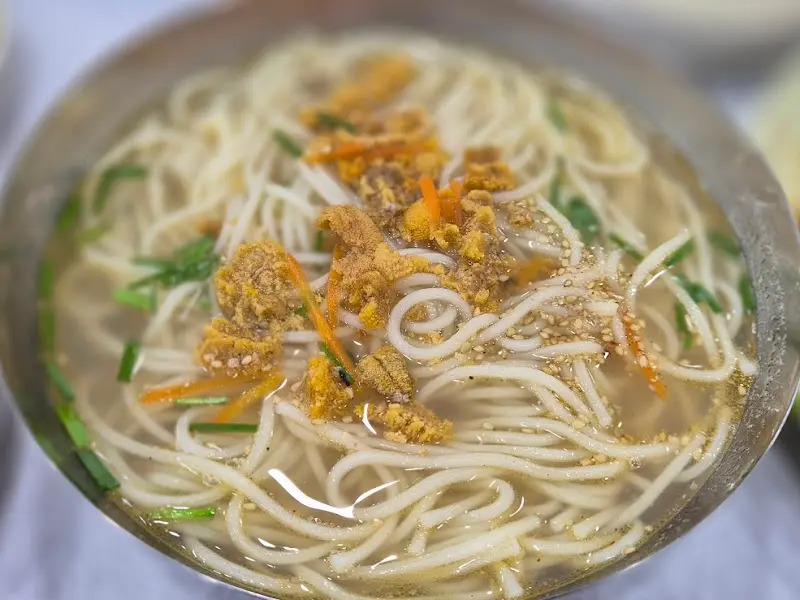 성게국수 클로즈업 사진. 뽀얀 국물과 듬뿍 올라간 성게알이 인상적이다.