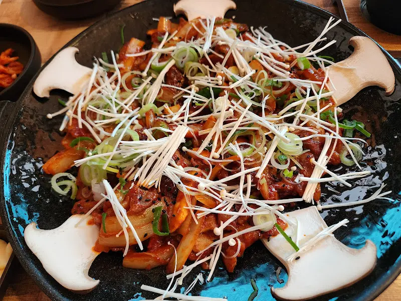 제육철판의 클로즈업 샷, 팽이버섯 토핑이 인상적이다.